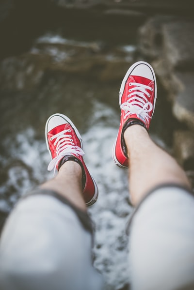 在水体上方穿着红色低帮运动鞋的人的选择性聚焦摄影